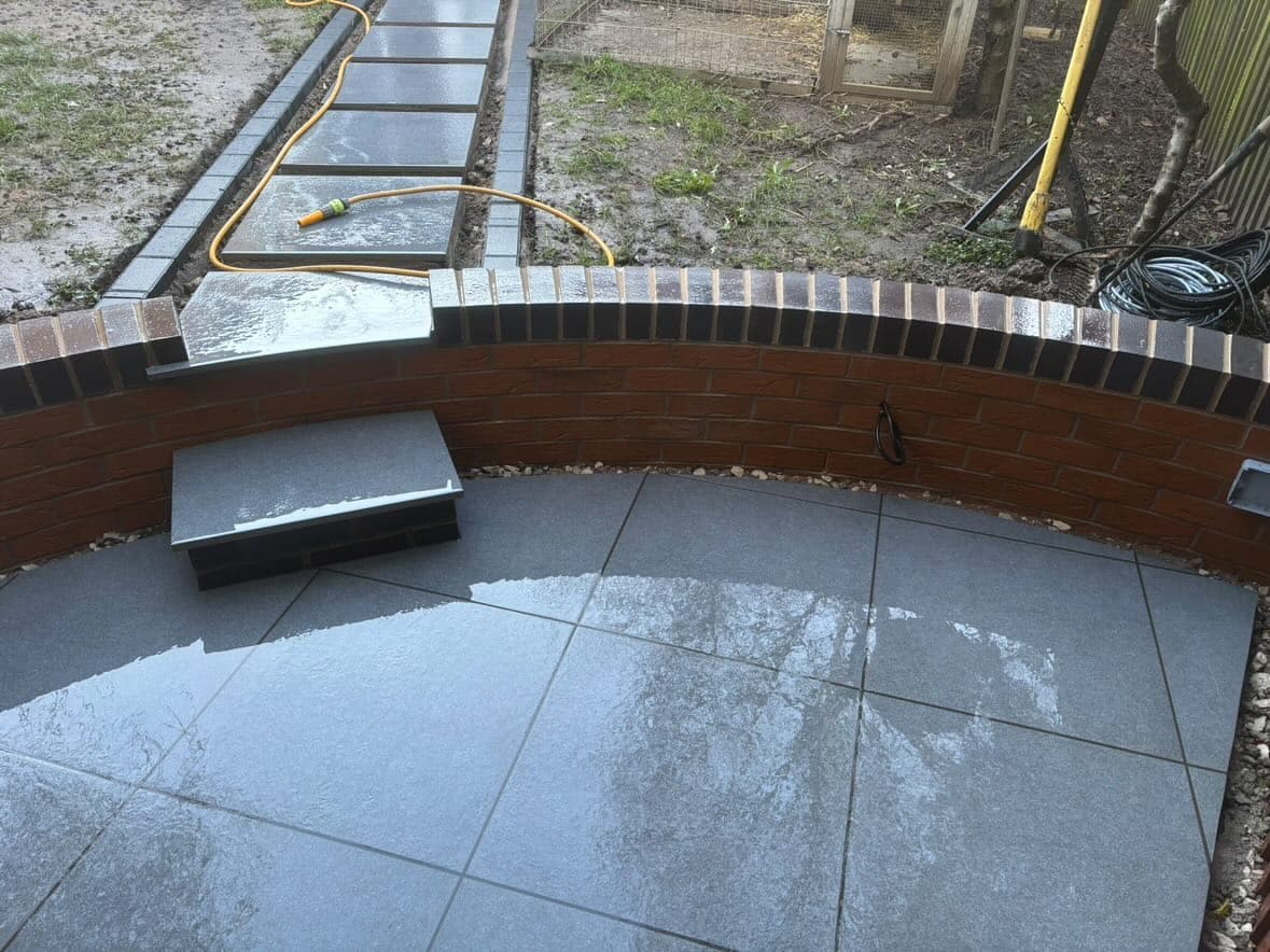 Porcelain slabs being laid inside a curved retaining wall during the build
